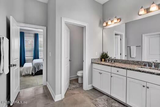 full bathroom with double vanity, toilet, baseboards, and a sink