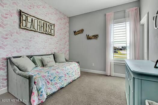 carpeted bedroom with wallpapered walls, an accent wall, and baseboards