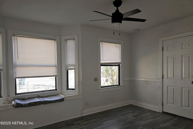 empty room with ceiling fan, baseboards, and dark wood-type flooring