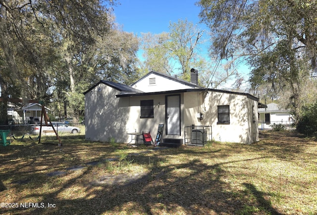 back of house with a yard, entry steps, fence, and a chimney