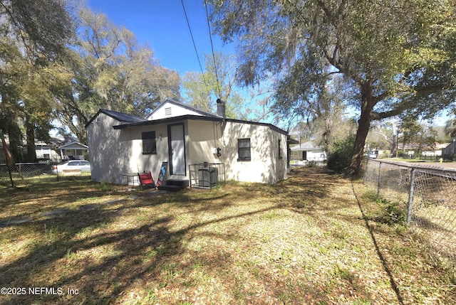 back of house featuring a fenced backyard, a yard, and a chimney