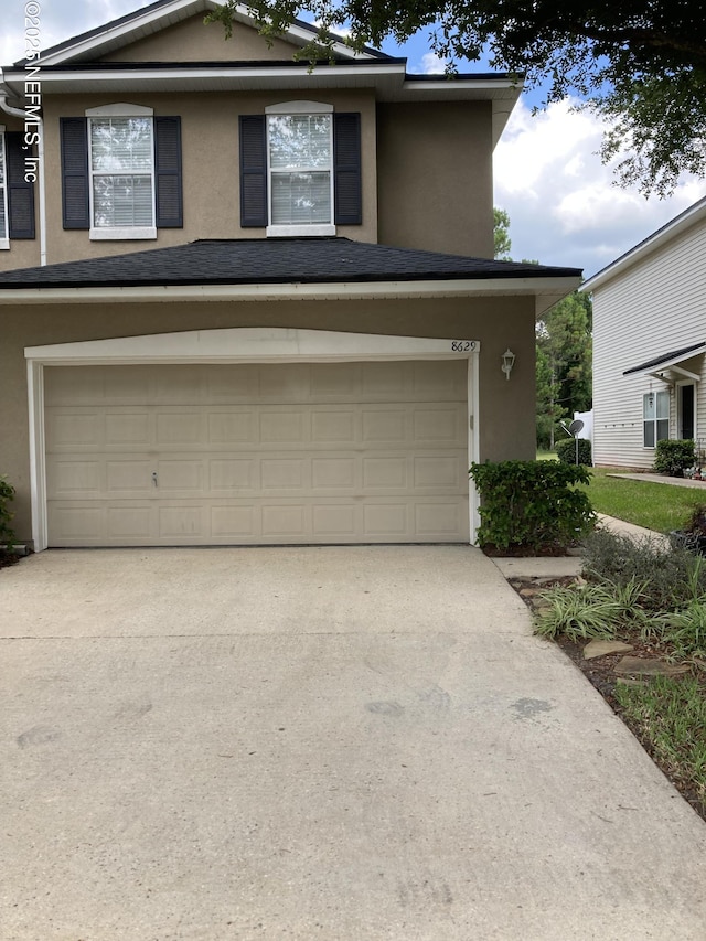 traditional-style home with stucco siding, concrete driveway, and a garage