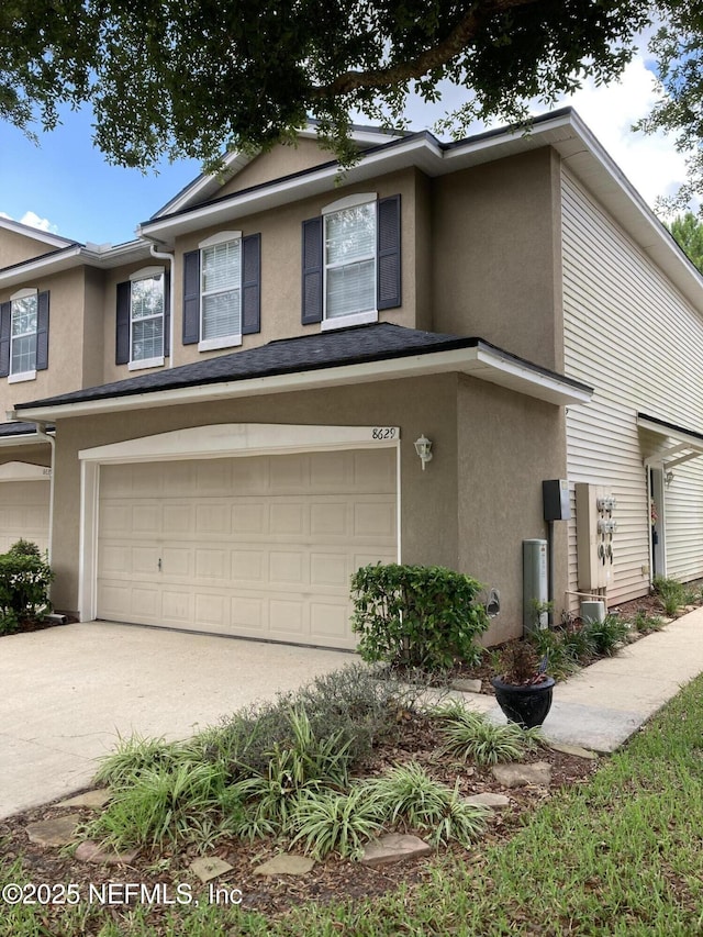 view of property featuring stucco siding, a garage, and driveway