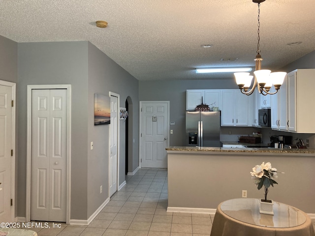 kitchen featuring light tile patterned floors, stainless steel fridge with ice dispenser, arched walkways, black microwave, and a chandelier