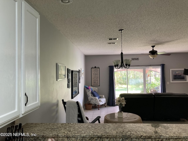 dining area featuring visible vents, a textured ceiling, tile patterned flooring, and ceiling fan with notable chandelier