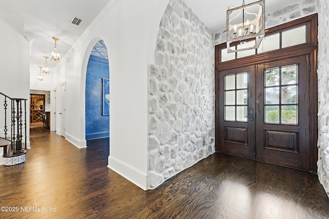 foyer with visible vents, a chandelier, stairway, ornamental molding, and wood finished floors