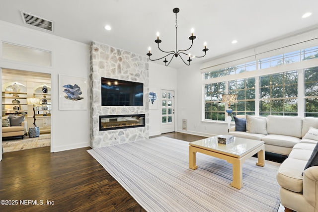 living area with dark wood-style floors, visible vents, a healthy amount of sunlight, and a large fireplace