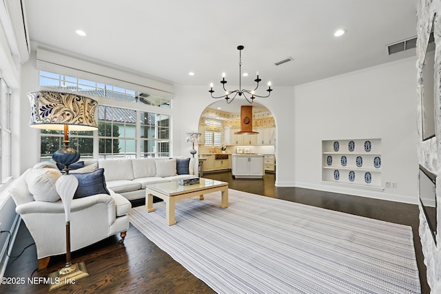 living room featuring arched walkways, visible vents, dark wood finished floors, and built in shelves