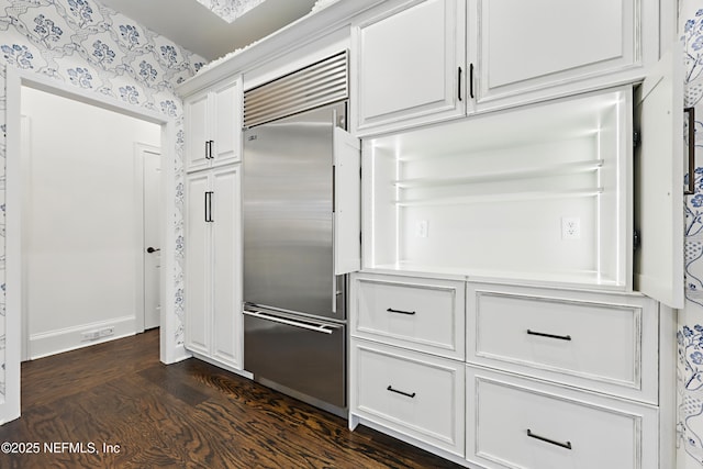 kitchen with built in refrigerator, white cabinetry, dark wood-style flooring, and wallpapered walls