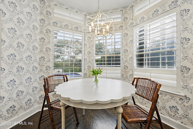 dining area featuring wallpapered walls, baseboards, breakfast area, wood finished floors, and a notable chandelier