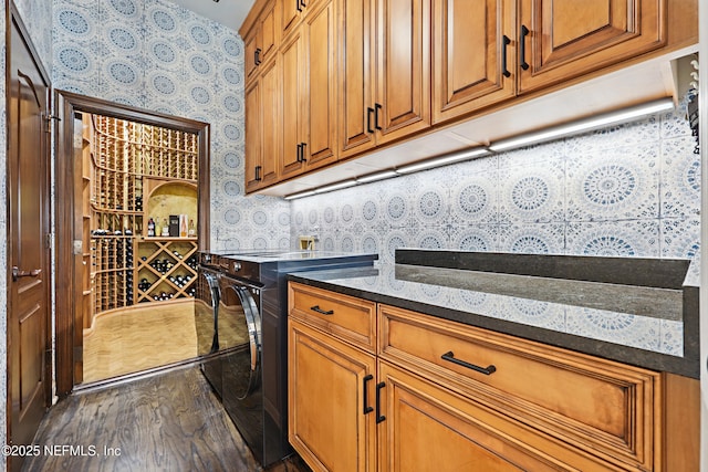 interior space featuring wallpapered walls, dark stone counters, range, brown cabinetry, and dark wood-style flooring