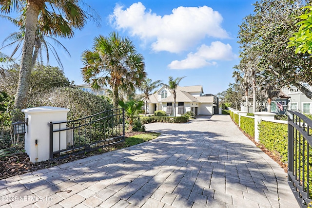 view of front of property with a gate, decorative driveway, a fenced front yard, and stucco siding