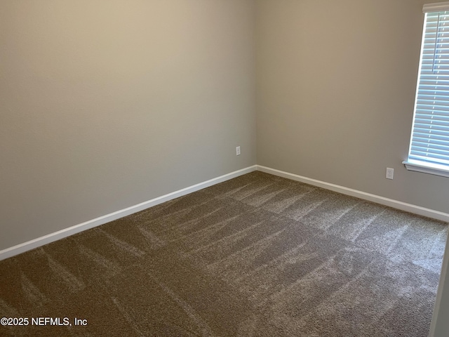 unfurnished room featuring dark colored carpet and baseboards