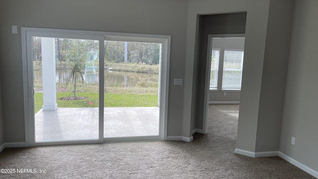 entryway with carpet, a water view, and baseboards