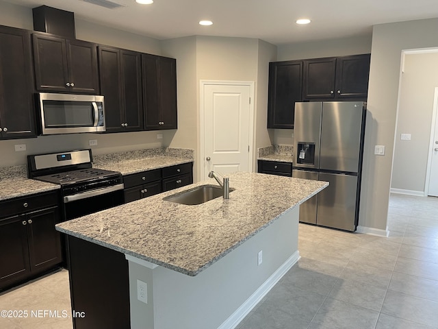 kitchen with a sink, light stone countertops, recessed lighting, stainless steel appliances, and a kitchen island with sink