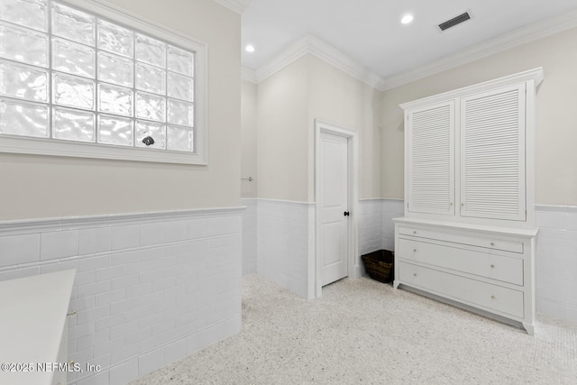 unfurnished bedroom featuring visible vents, recessed lighting, ornamental molding, wainscoting, and tile walls