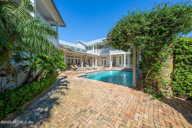 outdoor pool with french doors, ceiling fan, and a patio area
