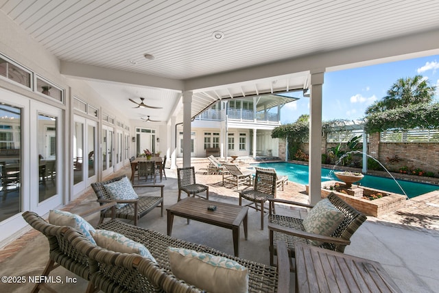view of patio / terrace featuring french doors, outdoor lounge area, a balcony, an outdoor pool, and a ceiling fan