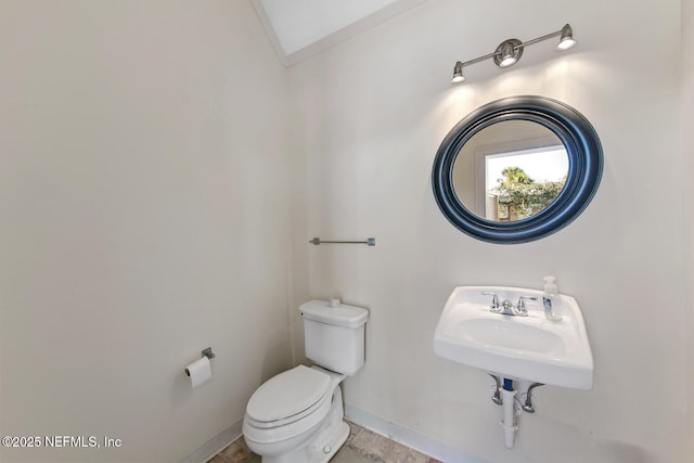 half bathroom featuring crown molding, toilet, baseboards, and a sink