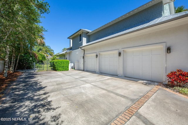 view of property exterior with a gate, fence, driveway, an attached garage, and stucco siding