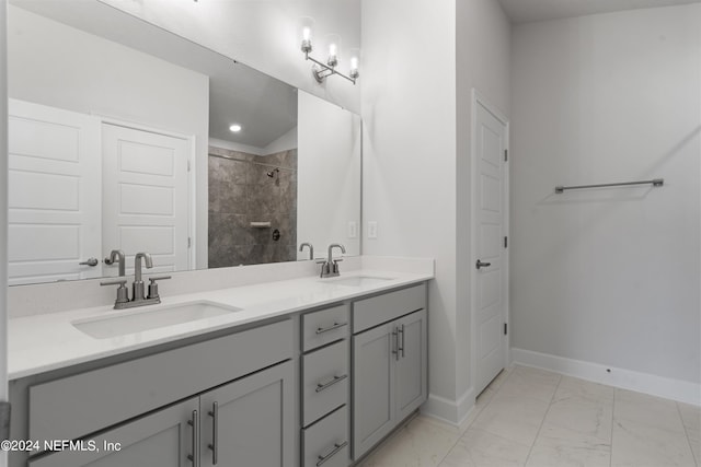 bathroom featuring a tile shower, marble finish floor, a sink, and baseboards