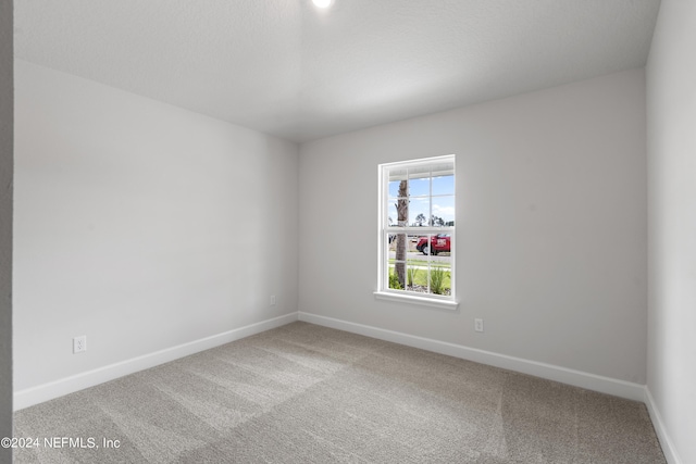 carpeted spare room featuring baseboards