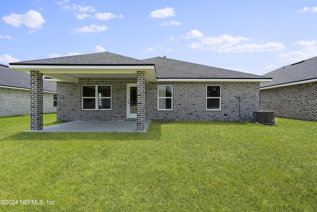 rear view of house with a shingled roof, central AC unit, a lawn, a patio area, and brick siding