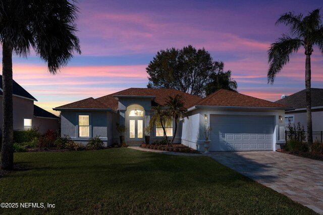 single story home with stucco siding, a front lawn, decorative driveway, french doors, and a garage