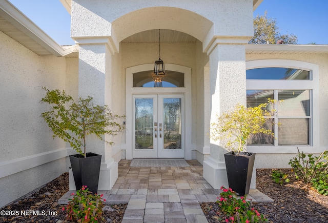 view of exterior entry featuring french doors and stucco siding