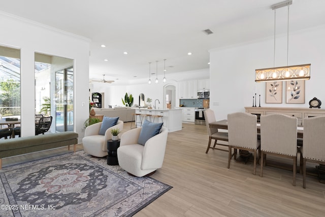 living area with recessed lighting, visible vents, ornamental molding, and light wood-style flooring