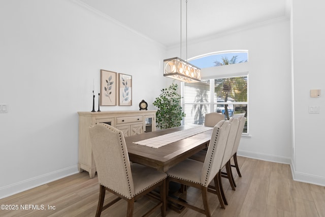 dining room featuring crown molding, baseboards, and light wood finished floors