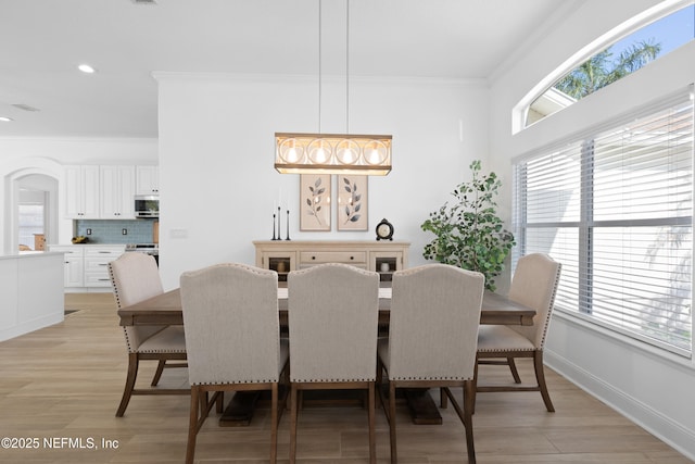 dining area featuring a wealth of natural light, light wood-type flooring, crown molding, and baseboards