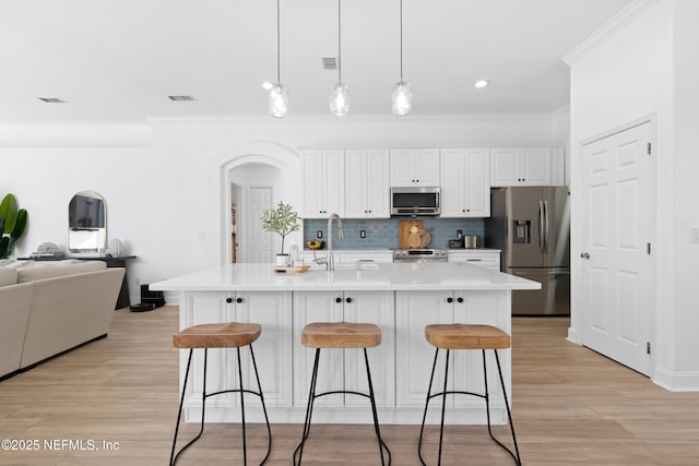 kitchen featuring a sink, ornamental molding, stainless steel appliances, a kitchen breakfast bar, and open floor plan