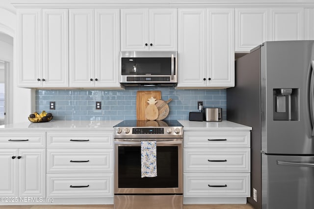 kitchen with stainless steel appliances, backsplash, white cabinets, and light countertops