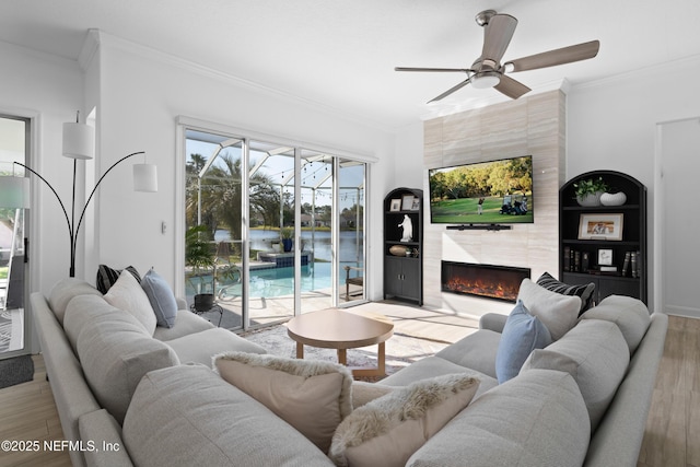 living area featuring a premium fireplace, ornamental molding, a sunroom, and wood finished floors