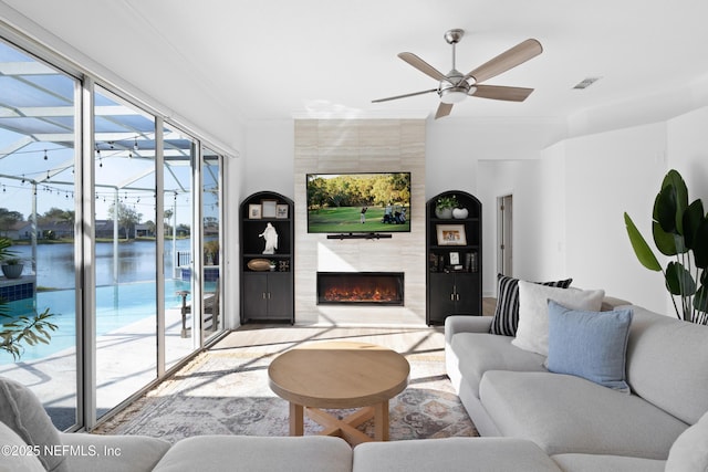 living room featuring ceiling fan, visible vents, ornamental molding, and a high end fireplace