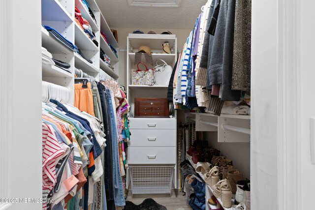 walk in closet with attic access and wood finished floors