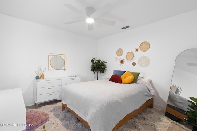 bedroom featuring light wood finished floors, visible vents, baseboards, and a ceiling fan