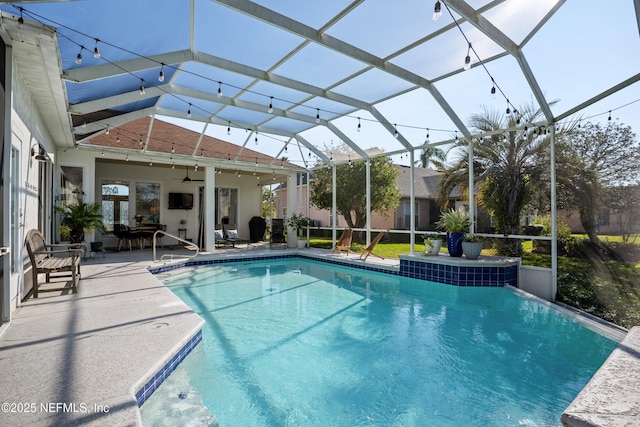 outdoor pool featuring glass enclosure, a ceiling fan, and a patio