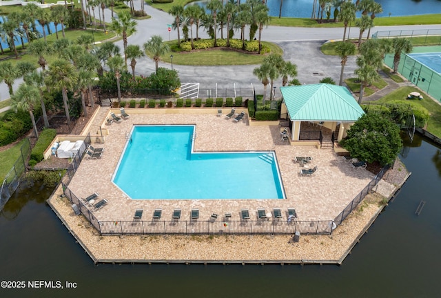 view of swimming pool featuring fence, a patio, and a water view