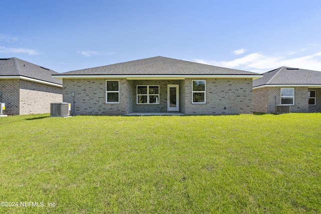 view of front facade with a shingled roof, a front lawn, cooling unit, and brick siding