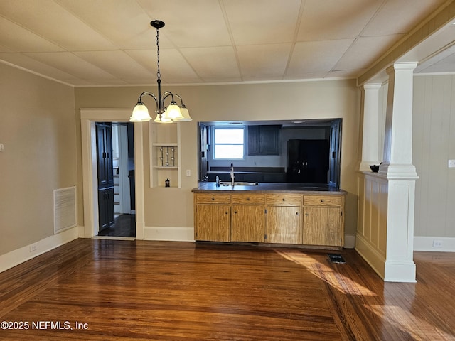 kitchen with decorative columns, dark wood-type flooring, a sink, and visible vents