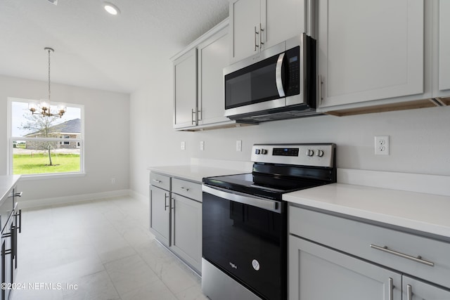 kitchen with appliances with stainless steel finishes, marble finish floor, light countertops, and an inviting chandelier