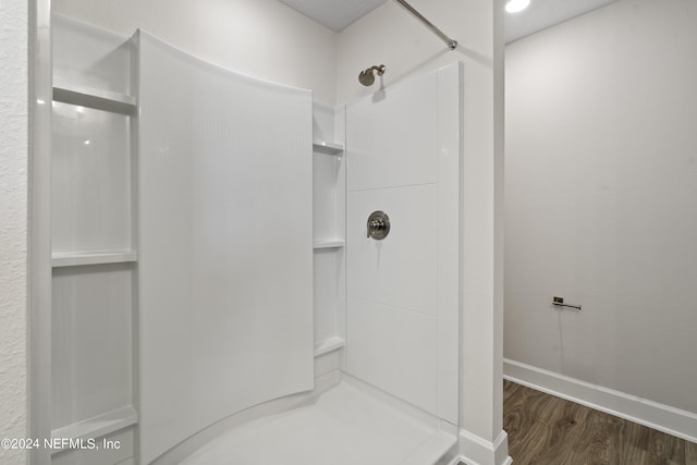 full bath featuring baseboards, walk in shower, and wood finished floors