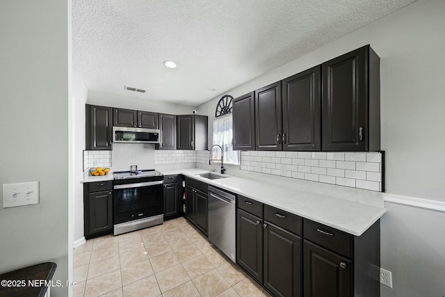 kitchen with visible vents, a sink, stainless steel appliances, light countertops, and tasteful backsplash