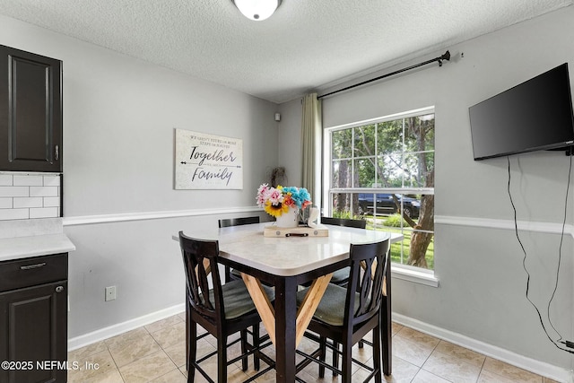 dining space featuring light tile patterned floors, baseboards, and a textured ceiling