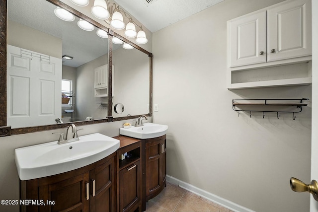 full bath featuring a sink, baseboards, double vanity, and tile patterned flooring