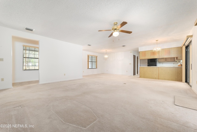 unfurnished living room featuring light colored carpet, visible vents, and a wealth of natural light