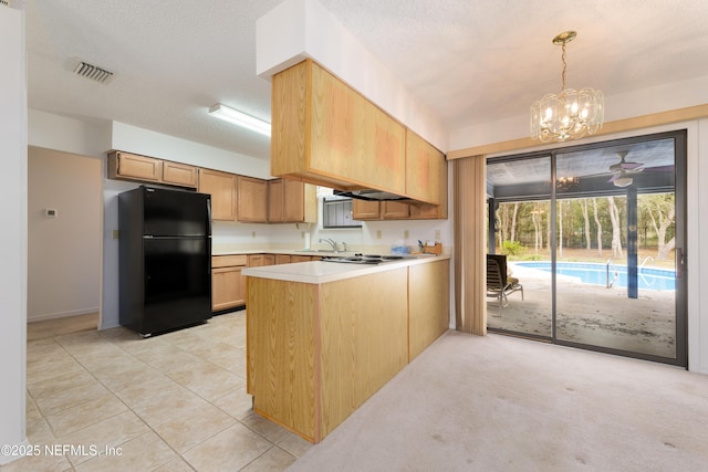 kitchen with a sink, a textured ceiling, freestanding refrigerator, a peninsula, and light countertops