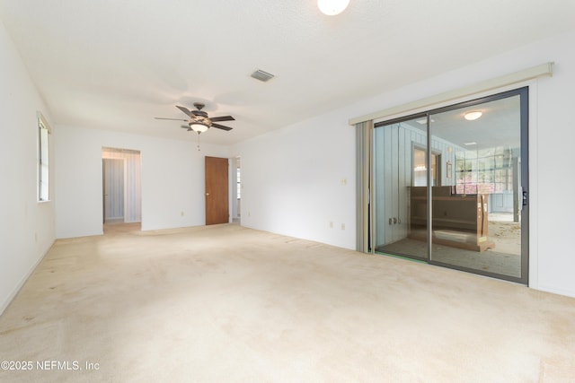 spare room featuring carpet flooring, visible vents, and ceiling fan